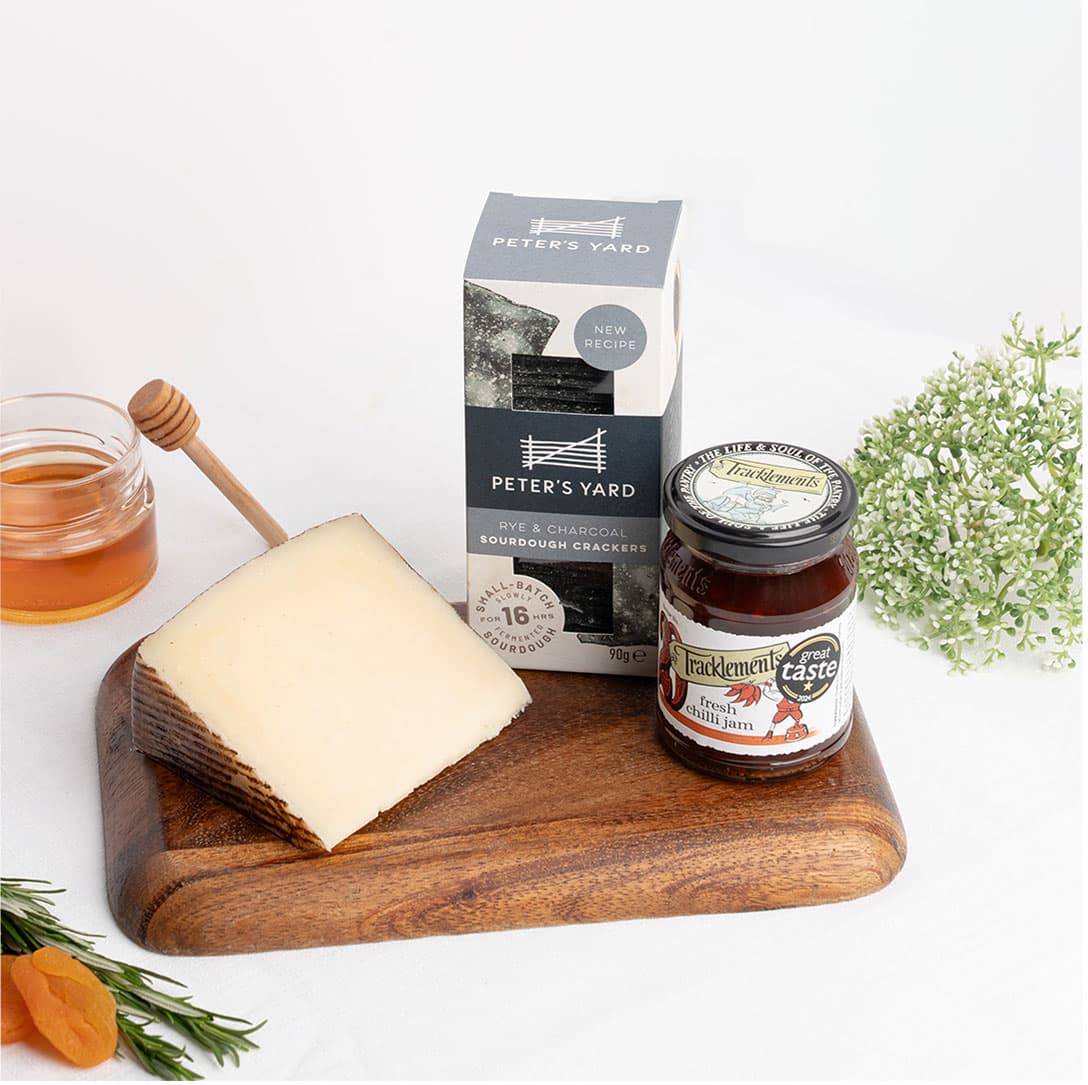 Premium sheep's milk Manchego served with charcoal sourdough crackers and artisan chilli jam for a refined tasting experience. Available for premium cheese delivery in Dubai.