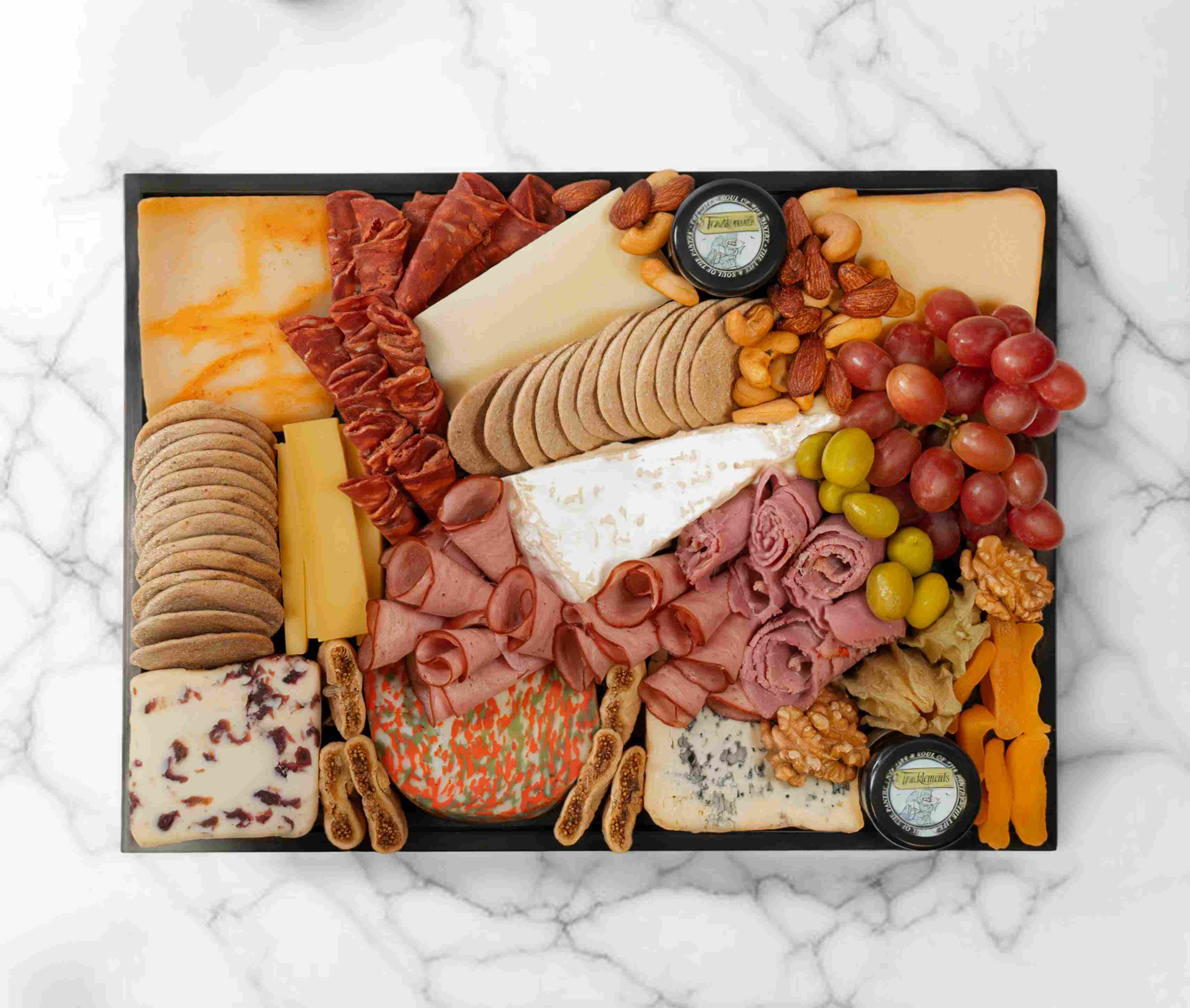 The Cheese Man’s signature cheeseboard with assorted cheeses, charcuterie, and fruits, serving 5–7 people.