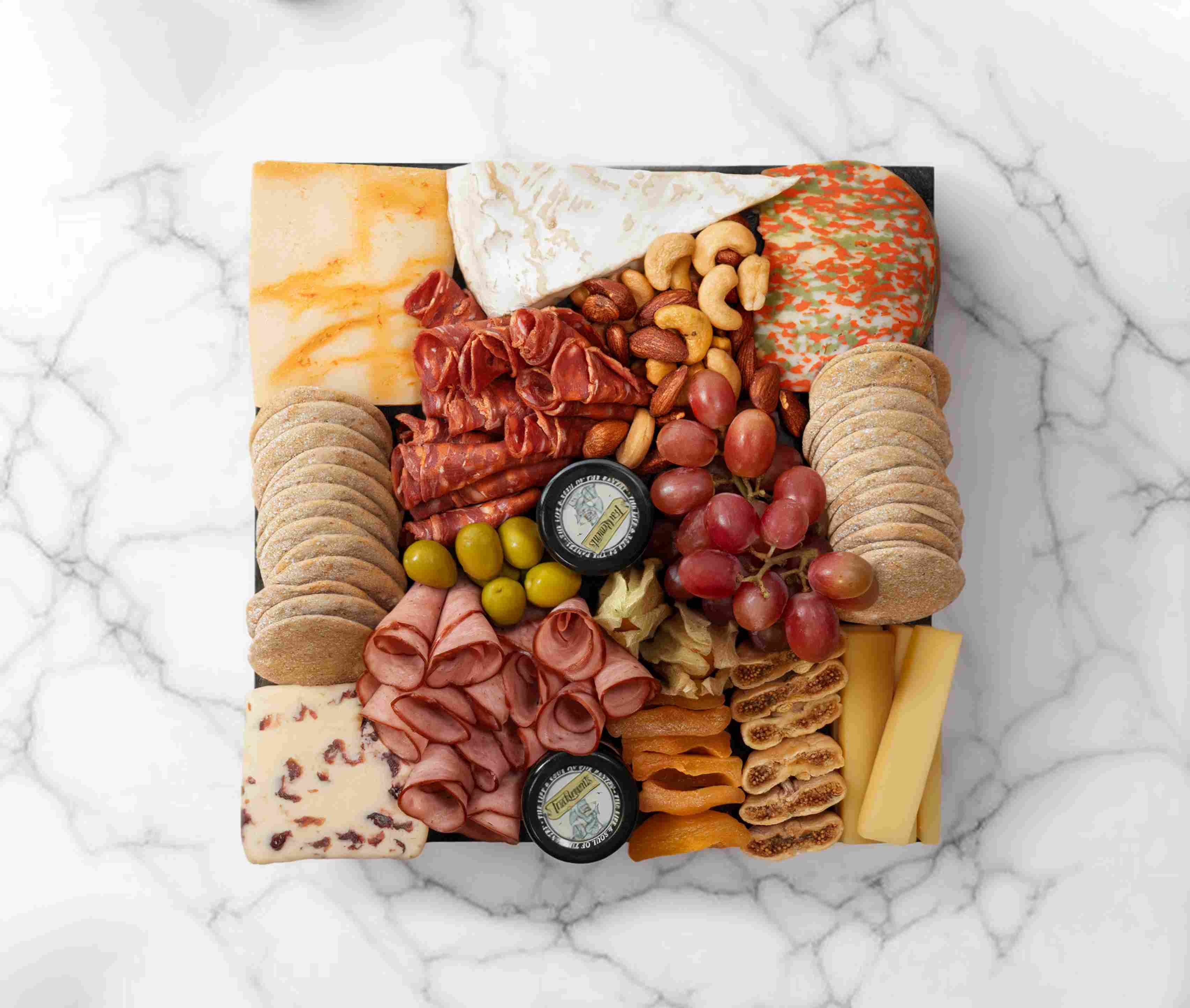 Signature cheeseboard by The Cheese Man with gourmet cheeses, charcuterie, and fruits, serving 2–4 people.