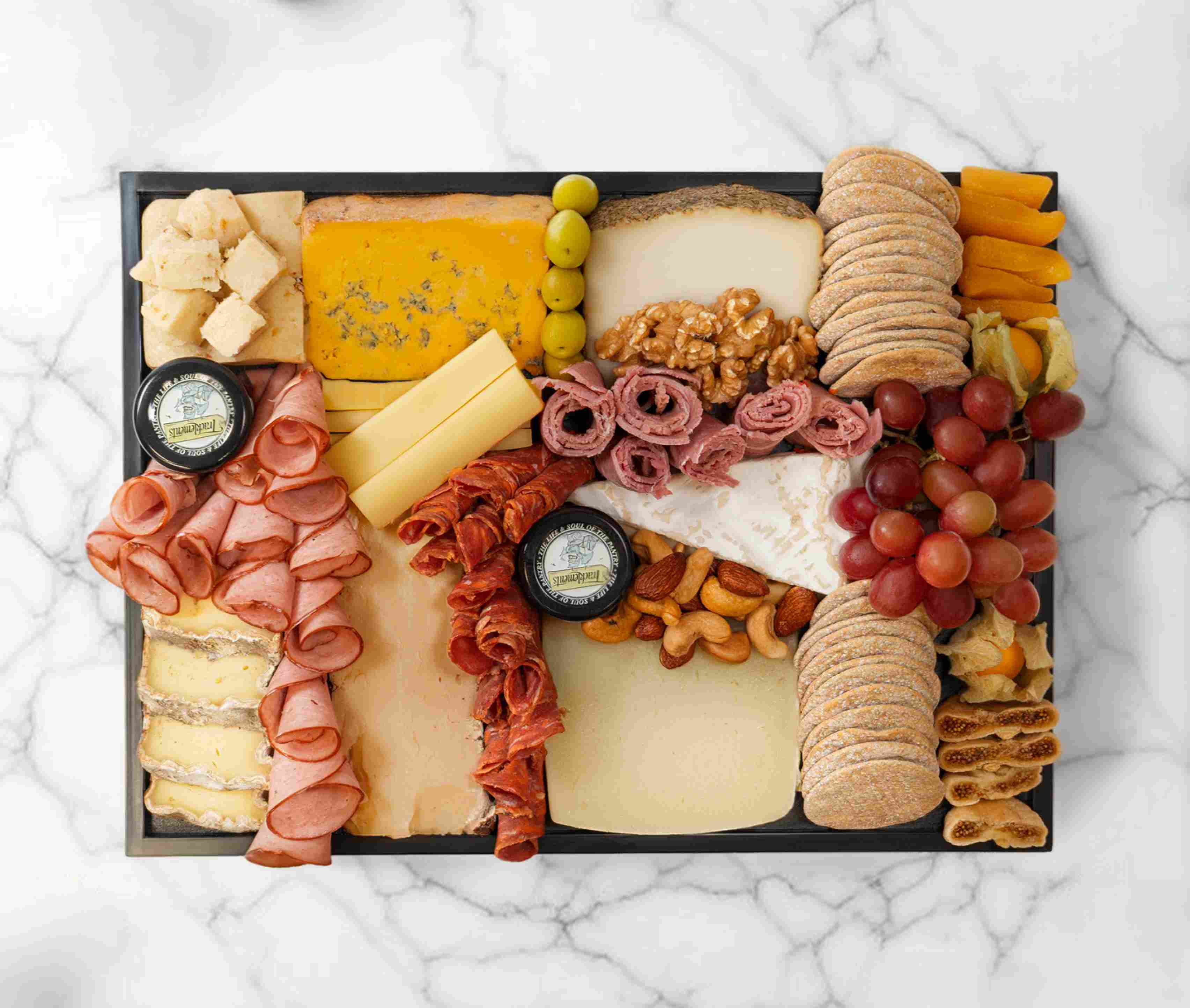 Medium premium cheeseboard with artisan cheeses, fruits, and accompaniments, serving 5–7 people.