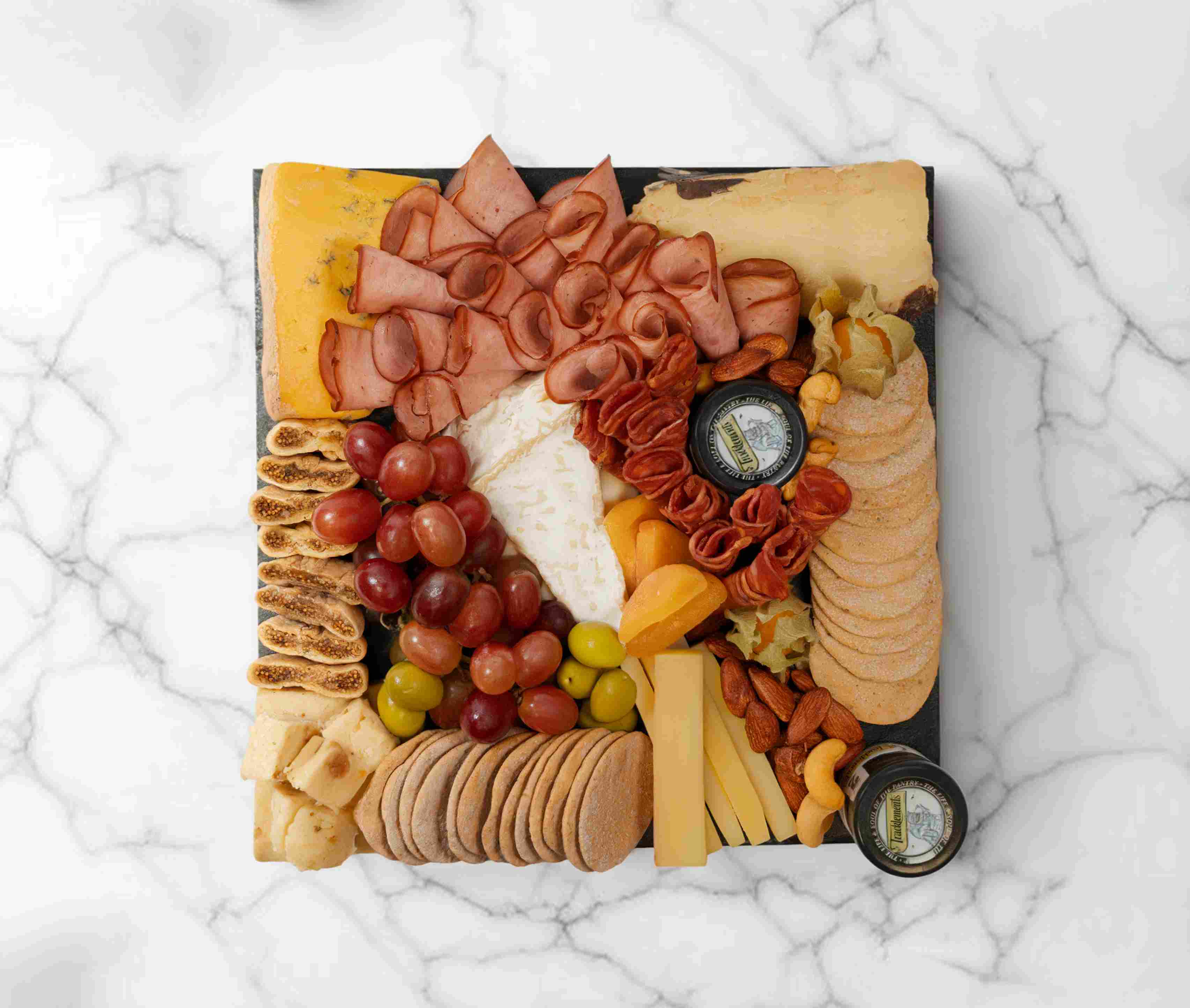 Premium cheeseboard with assorted artisan cheeses, fruits, and accompaniments, serving 2–4 people.