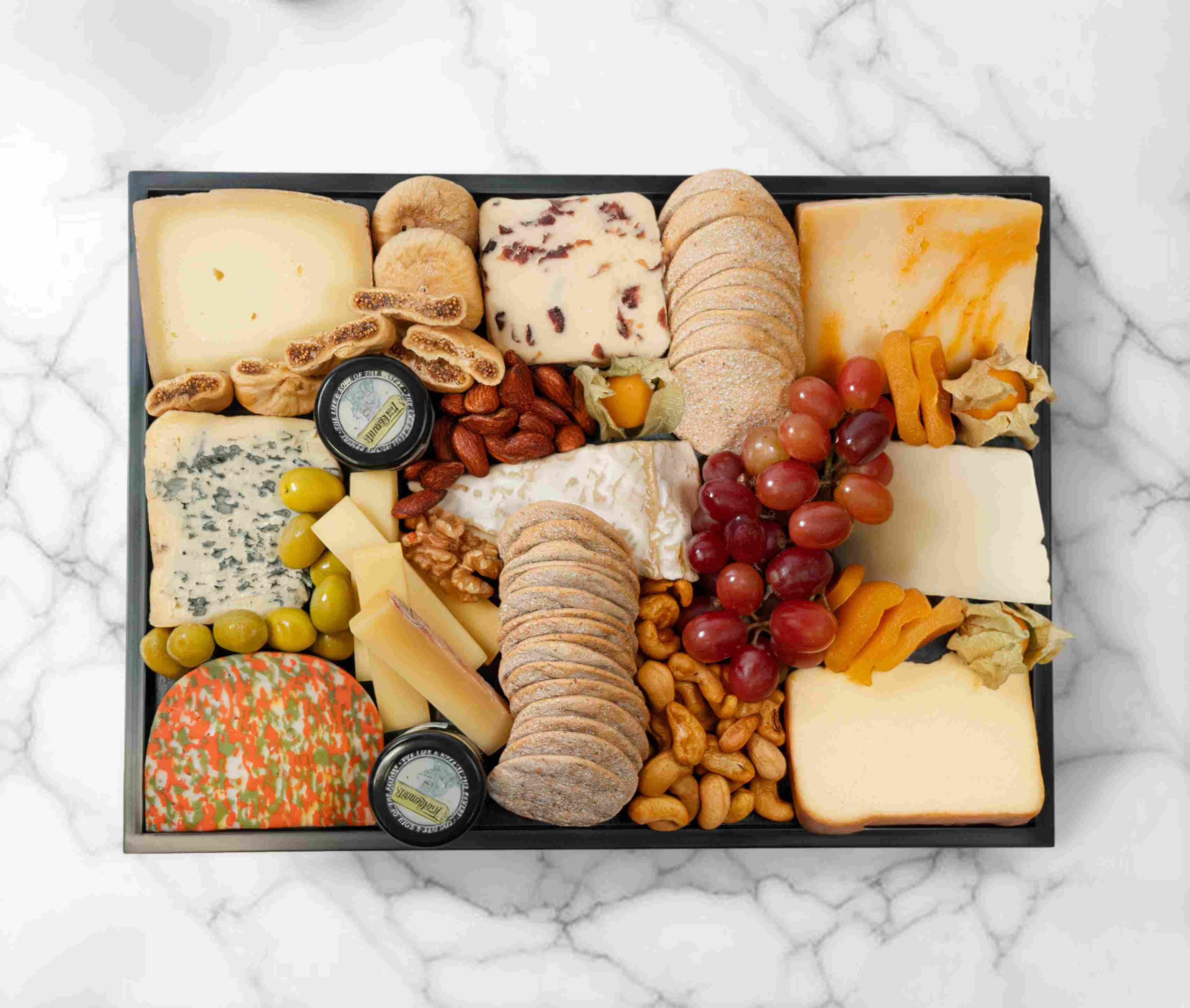 Large vegetarian cheeseboard with gourmet cheeses, fruits, and accompaniments, serving 5–7 people.