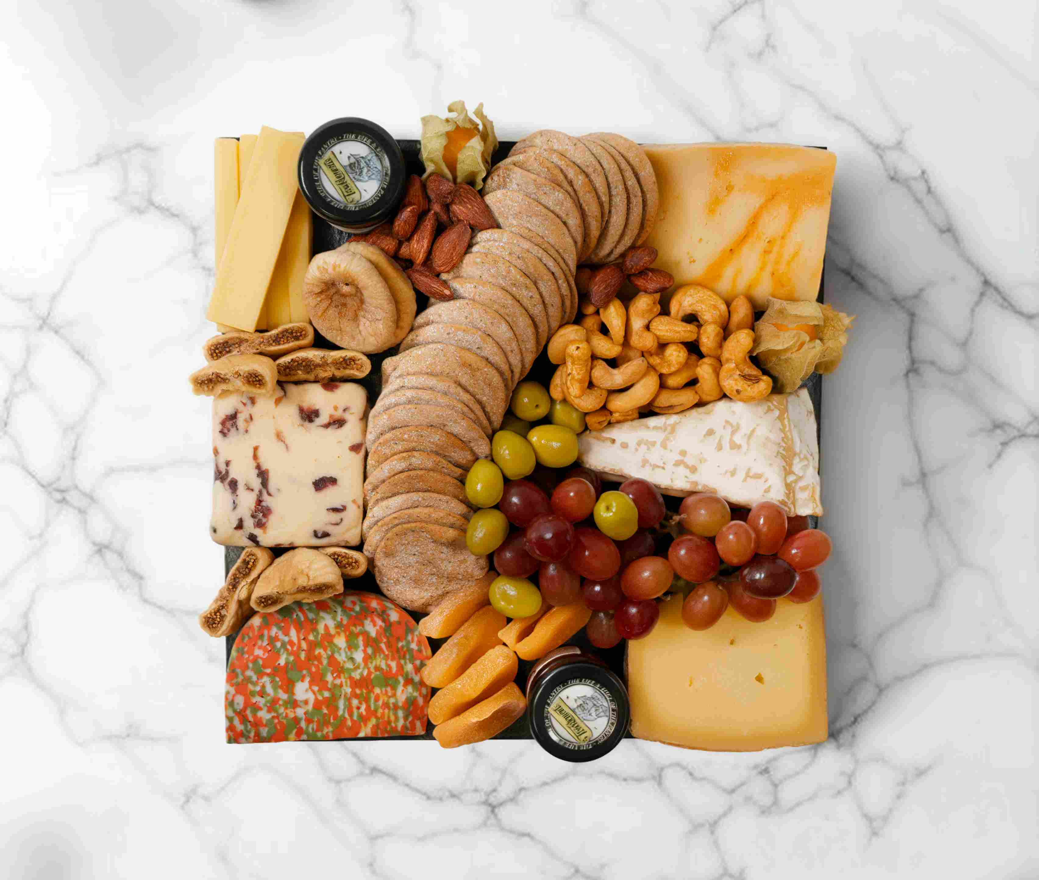 Vegetarian cheeseboard with assorted cheeses, fruits, and accompaniments, serving 2–4 people.